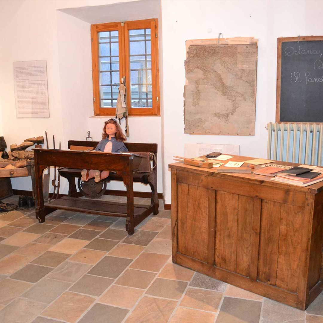 Interno del Museo Etnografico di Ostana: ricostruzione di un'aula scolastica d'epoca con banco, lavagna e carta geografica dell'Italia